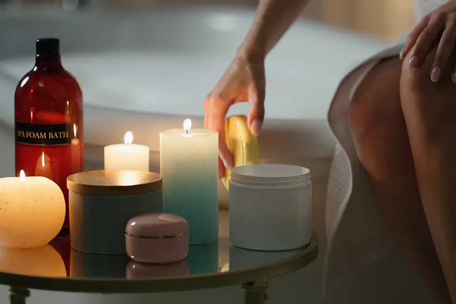 Candela profumata bianca accesa in un bagno moderno accanto a asciugamani e elementi naturali