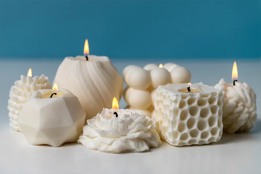 Candele artigianali minimaliste esposte su una mensola moderna con elementi naturali