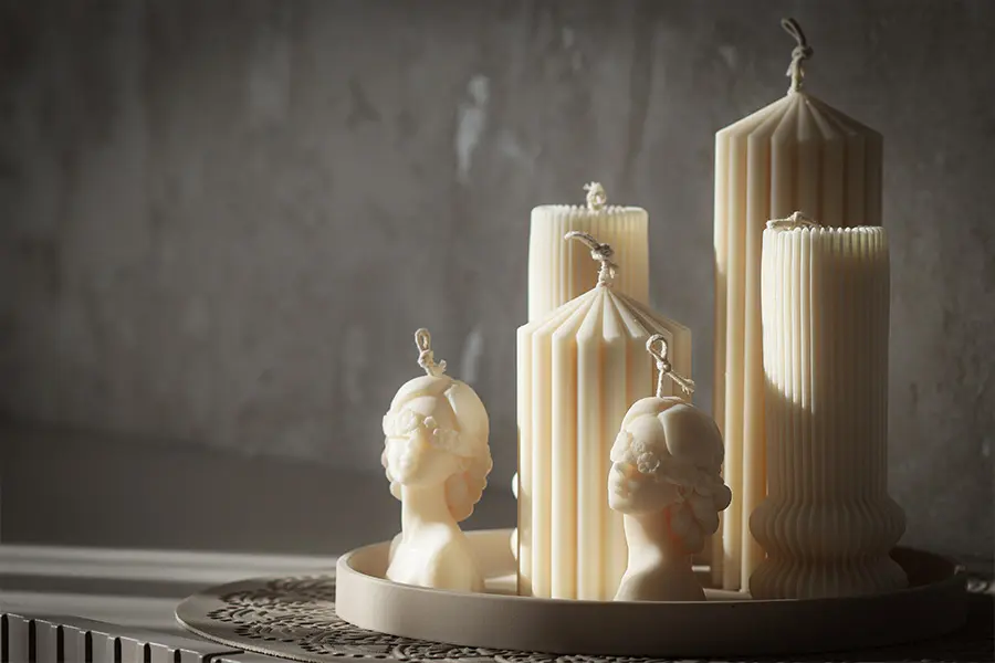 Candele decorative artistiche in forme scultoree posizionate su una consolle moderna con luce soffusa