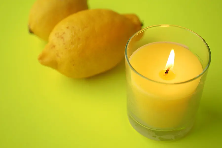 Candele repellenti eleganti a tre stoppini accese su un tavolino moderno in un balcone d'appartamento illuminato da luci calde